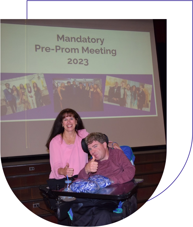 A man and woman posing for the camera in front of a projector screen.